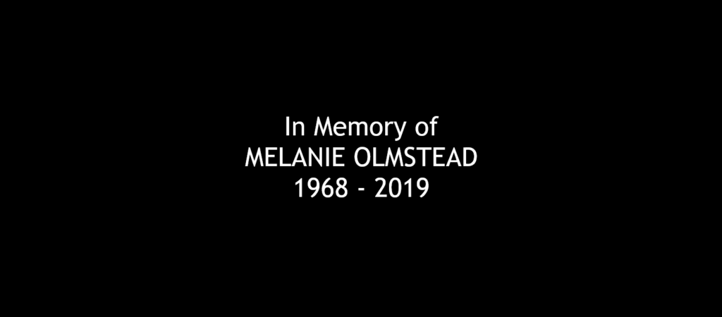 Der Screenshot zeigt einen schwarzen Hintergrund mit der folgenden weißen Schrift:

"In Memory of
MELANIE OLMSTEAD
1968 - 2019"

Dieser Moment stammt aus der Serie Yellowstone und erscheint in Staffel 2, Folge 10 (Die Sünden des Vaters), bei Timestamp 46:26. Er wird eingeblendet, um Melanie Olmstead zu gedenken, deren Leben und Arbeit eng mit der Serie verbunden waren.

Für viele Zuschauer ist dieser Moment von besonderem Interesse, da der Name Melanie Olmstead möglicherweise nicht sofort bekannt ist. Die Einblendung weckt Neugier und führt dazu, dass sich Fans fragen, wer sie war und welche Verbindung sie zur Serie hatte. Es ist eine berührende Geste, die aufzeigt, dass Melanie Olmstead hinter den Kulissen eine wichtige Rolle spielte, sei es in der Produktion, dem Transport oder der Unterstützung des Teams. Ihre Würdigung erinnert daran, dass erfolgreiche Projekte wie Yellowstone von den Beiträgen vieler unbesungener Helden abhängen.